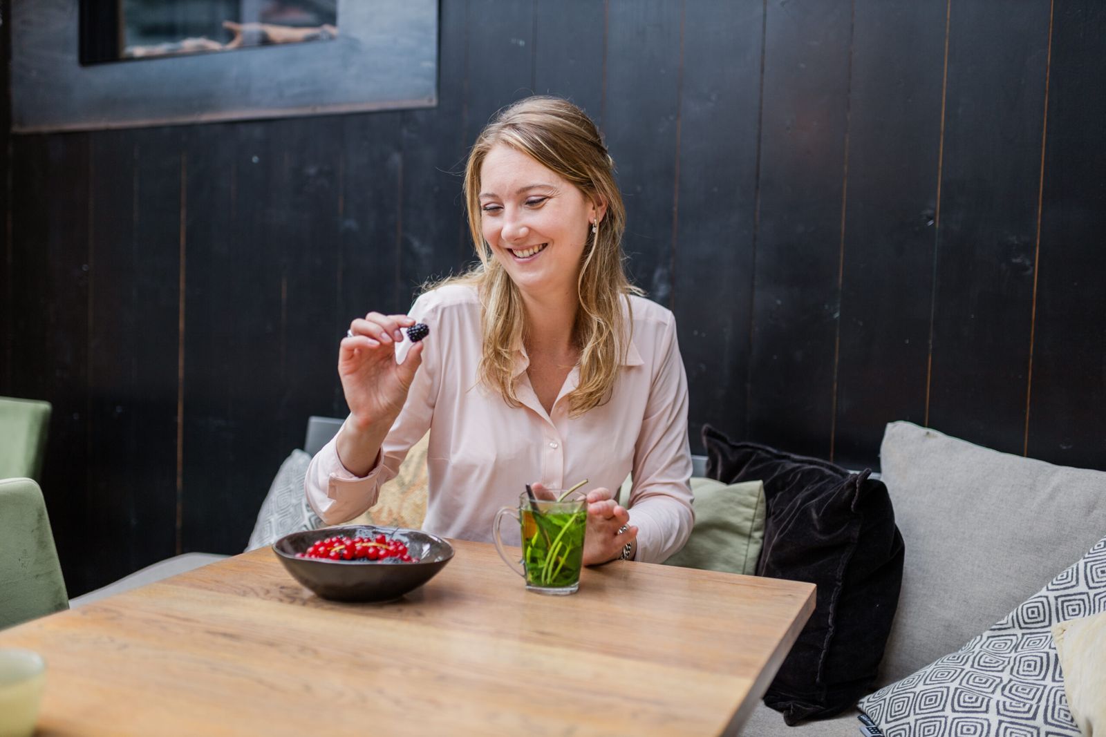 Wendy Reijnders pakt lachend een braam bij een schaal bessen en een glas muntthee